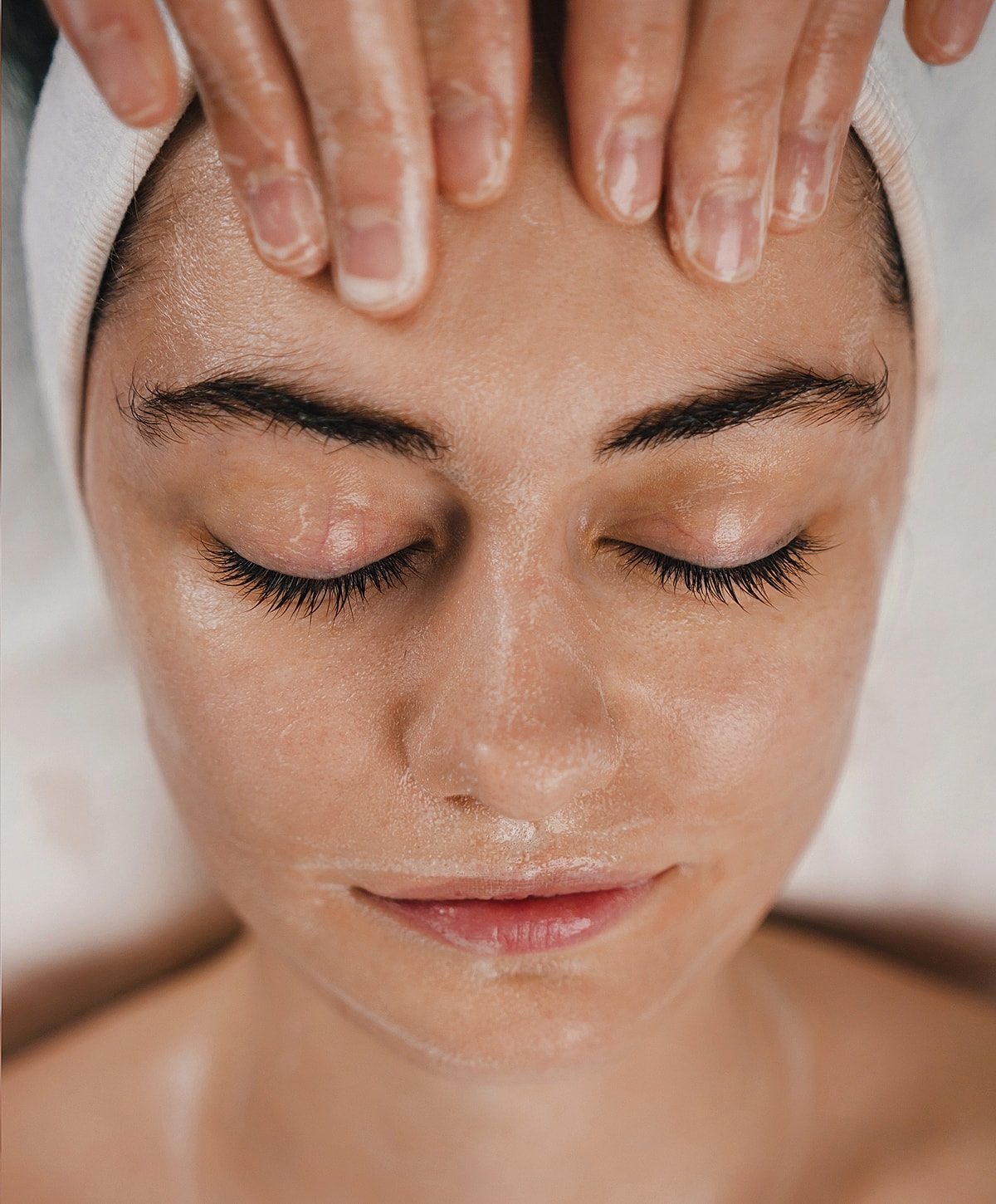 Woman receiving a facial treatment, eyes closed.