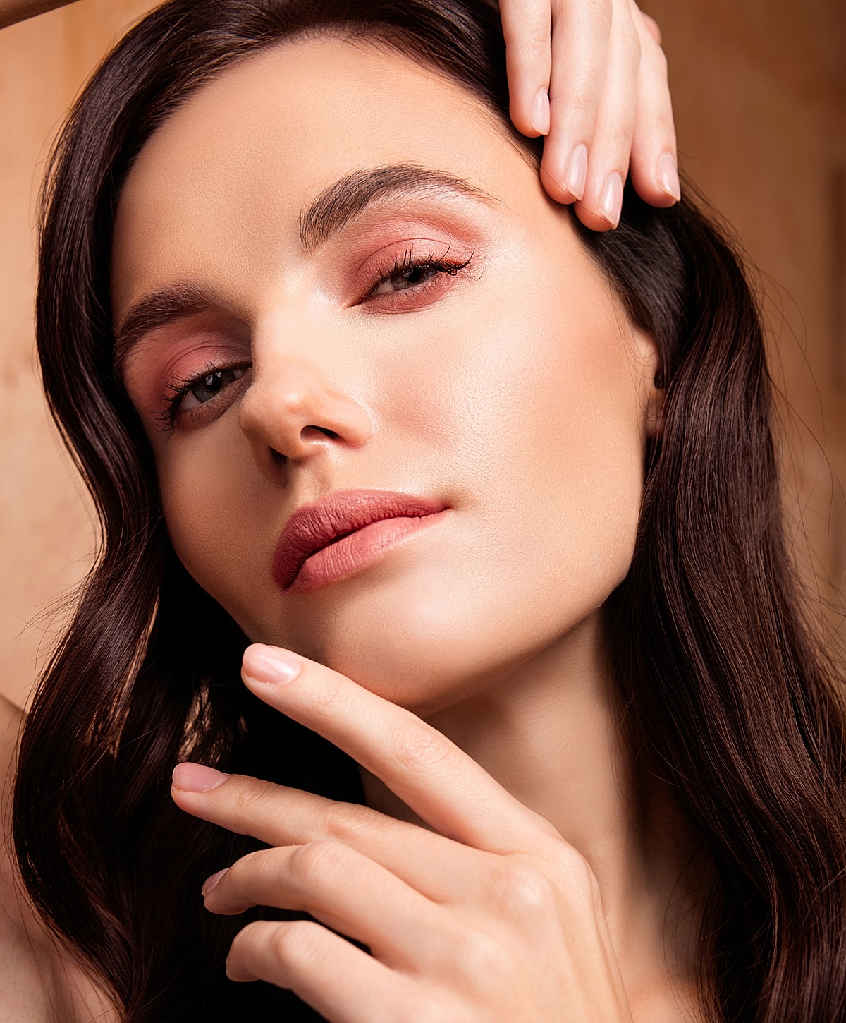 Close-up of woman's face with makeup and hands.
