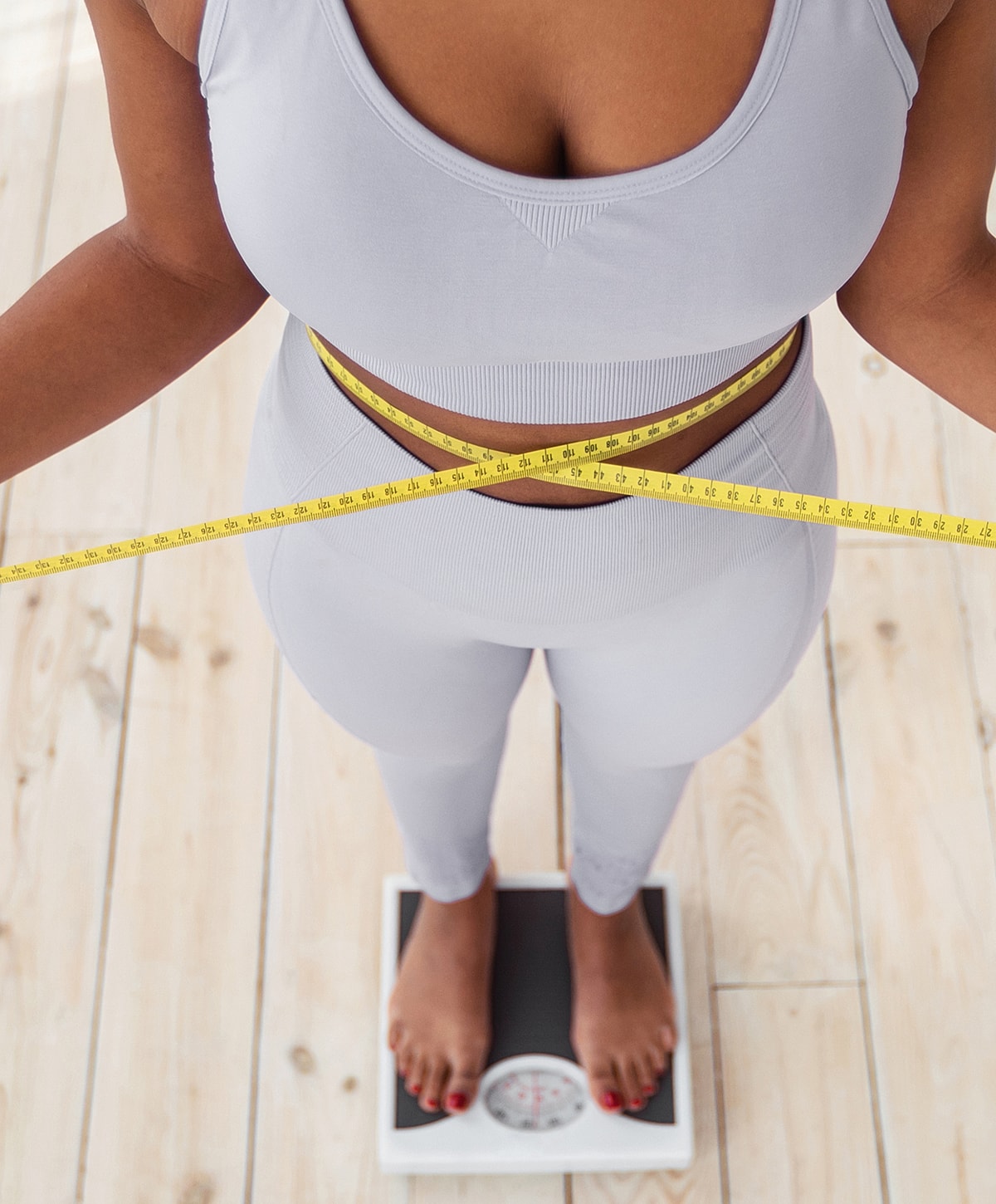 Person measuring waist while standing on scale