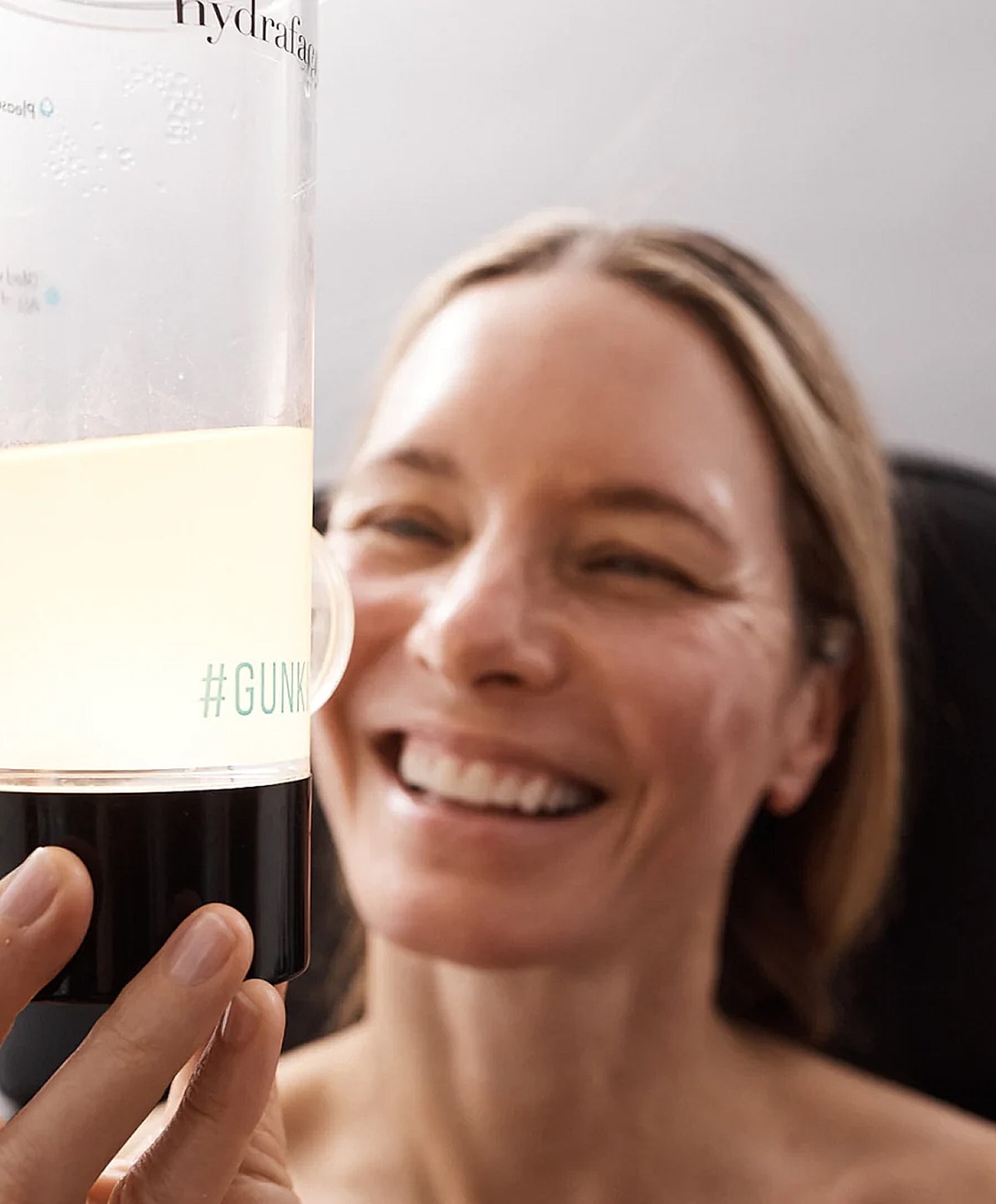 Woman smiling at hydrafacial device.