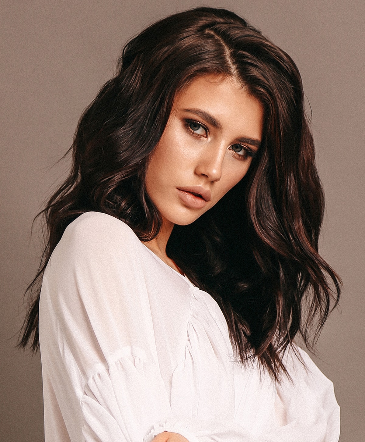 Woman with long wavy hair and natural makeup.