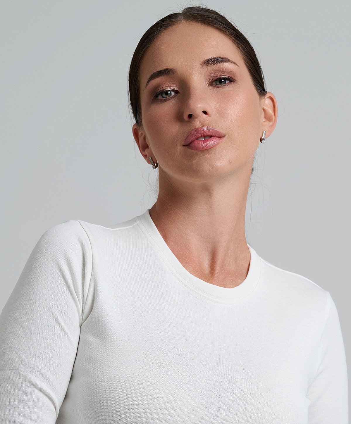 Woman in white long-sleeve shirt, neutral background.
