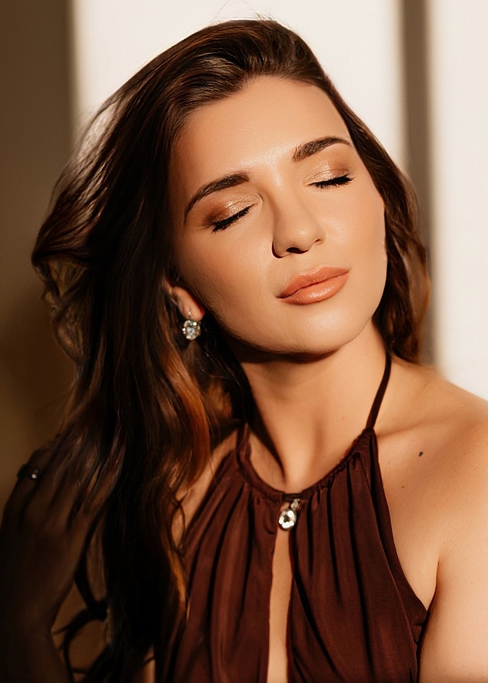 Woman with closed eyes, glowing skin, soft lighting.