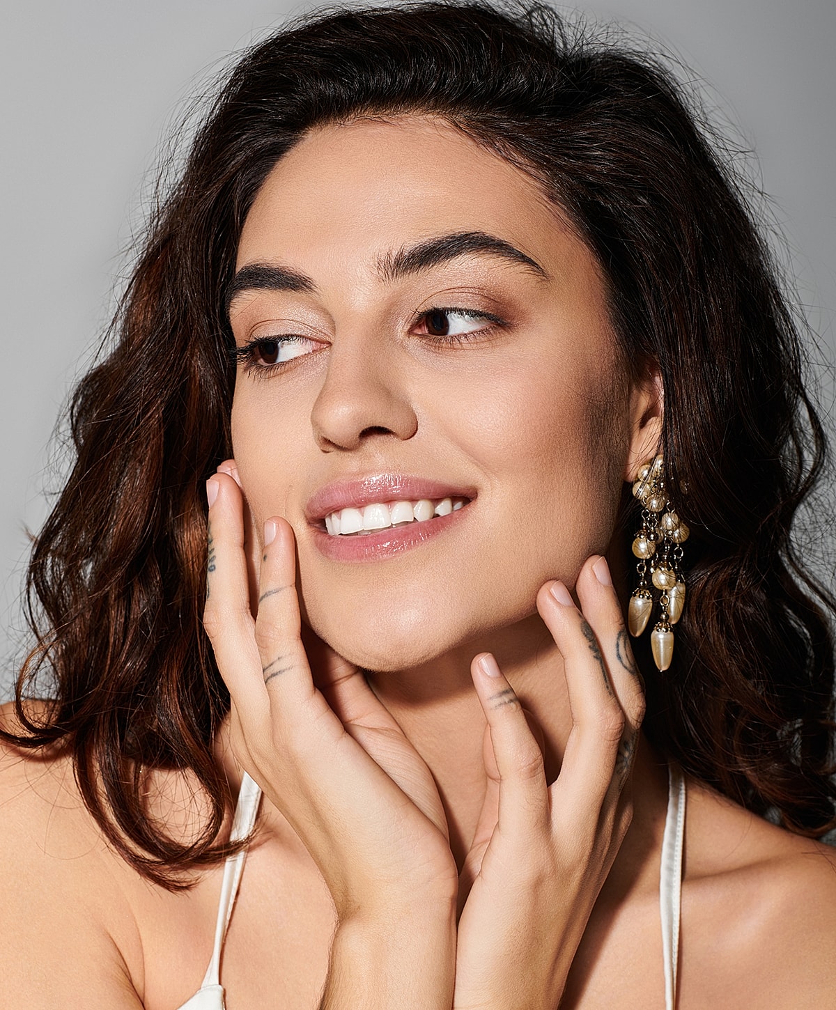 Smiling woman with jewelry and curly hair.