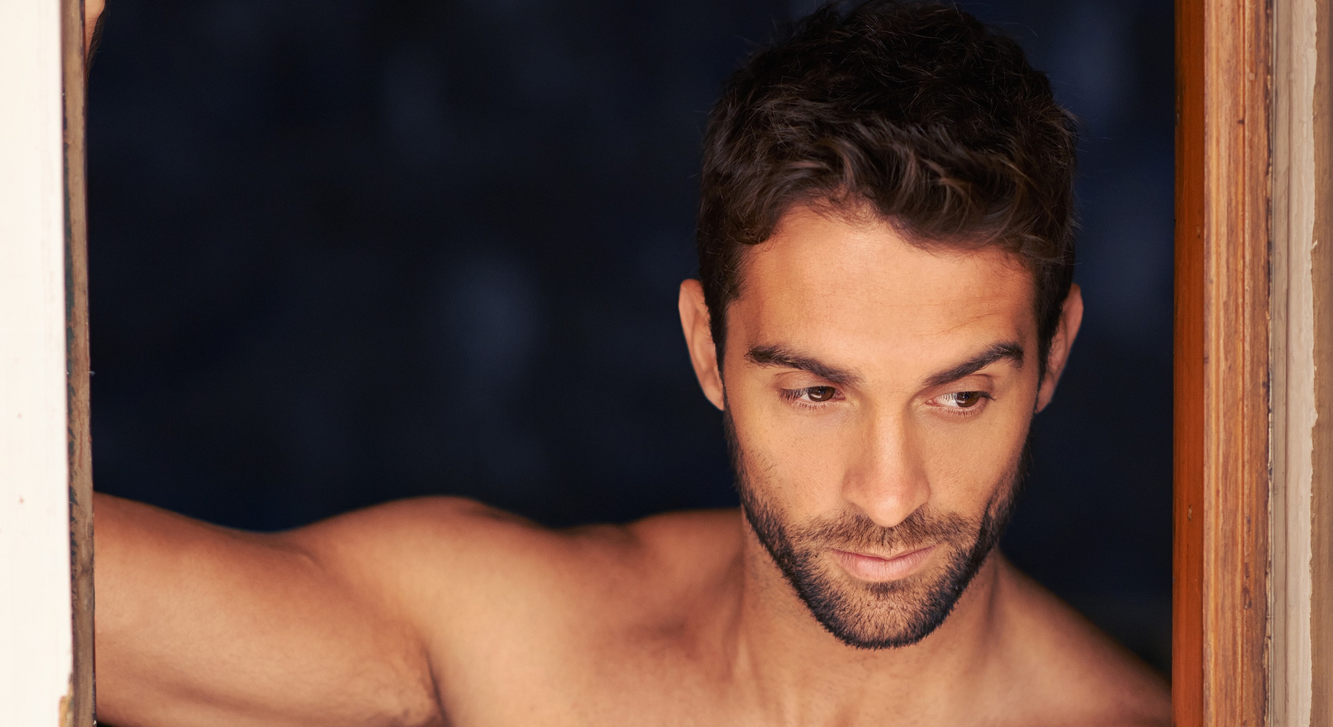 Man leaning against a doorway, deep in thought.